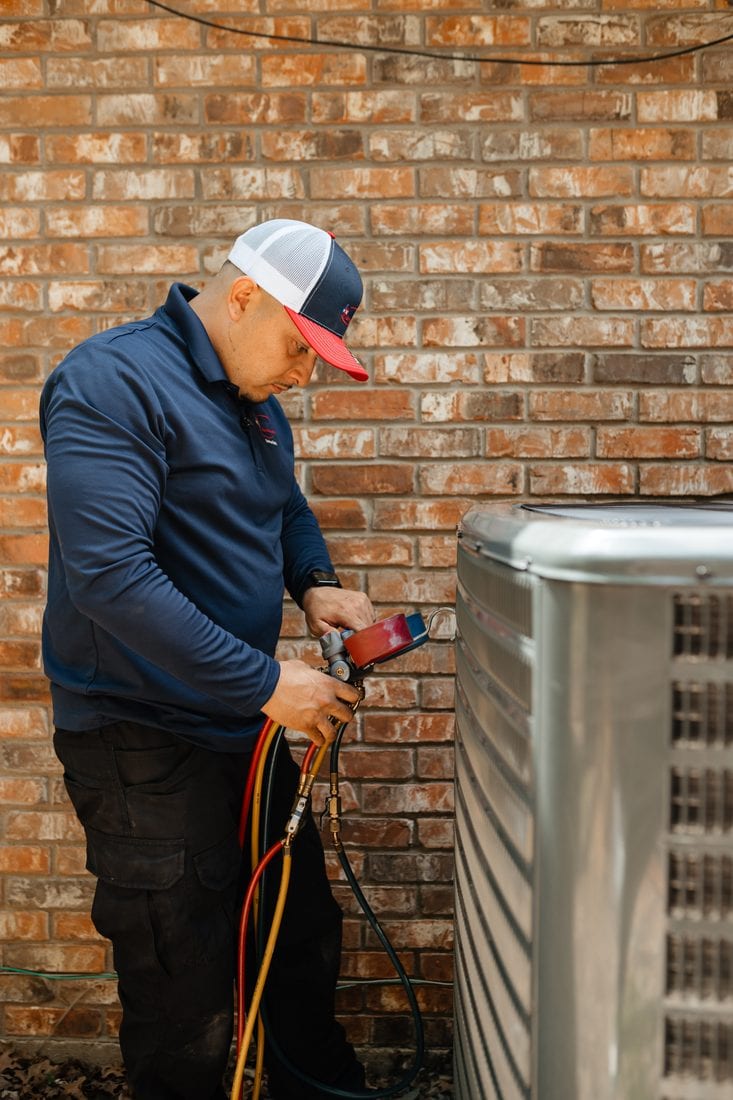 A Lexany's Heating & AC technician inspecting a heat pump outdoor unit