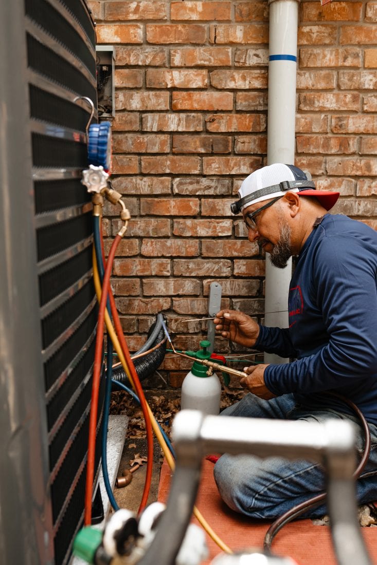A Lexany's technician working on an AC system's refrigerant lines